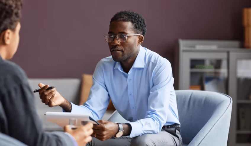 Two people sitting and discussing with notepad and pen