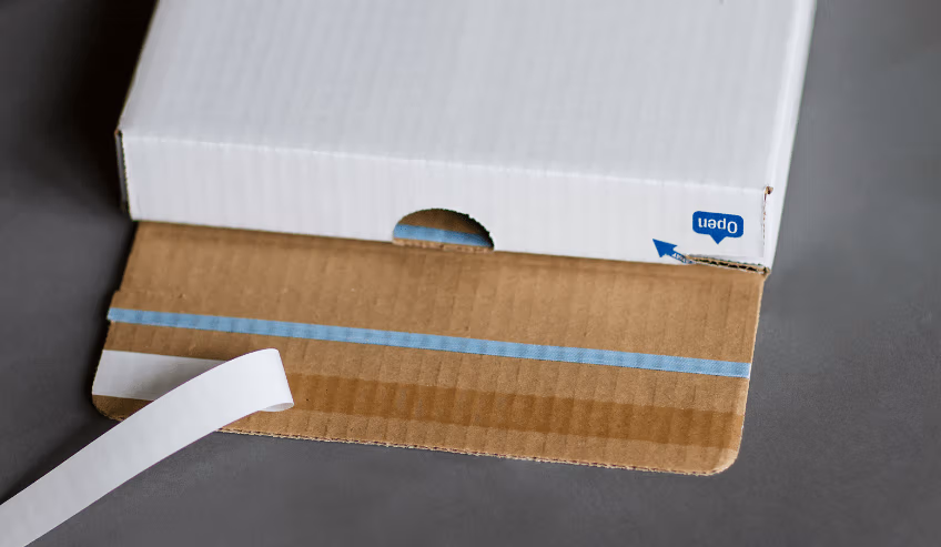 Double sided tape applied to opening of a white box