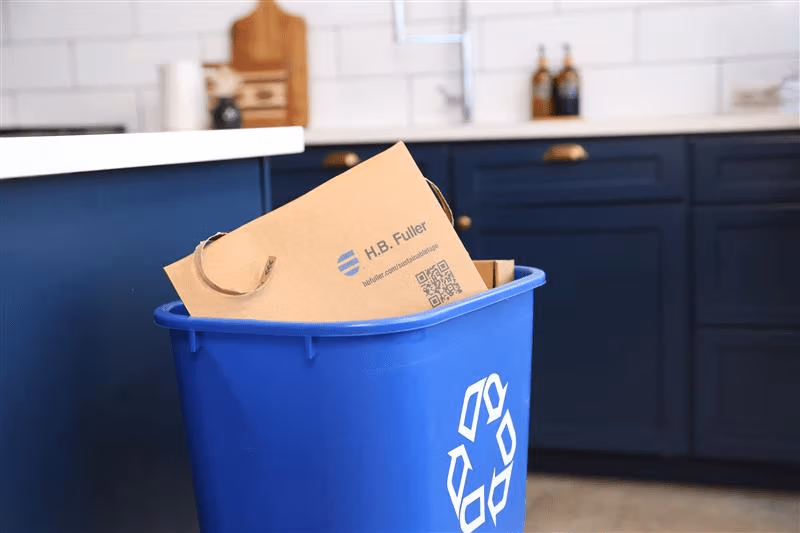 Sac brun dans une poubelle de recyclage bleue placée dans la cuisine