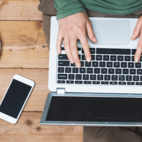 Person sitting and working on laptop and mobile phone