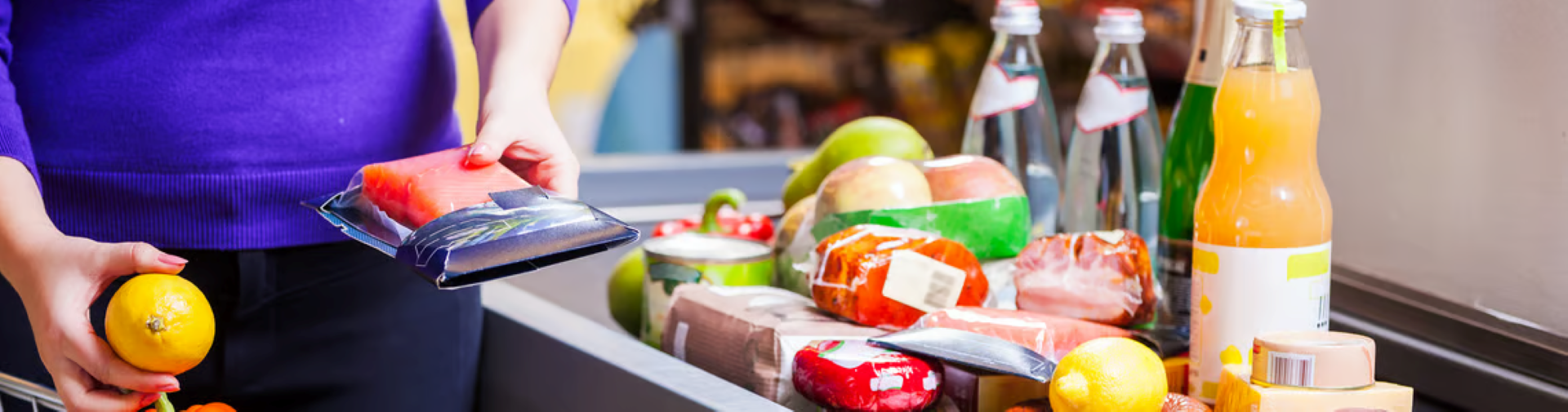 Person placing grocery items on a checkout conveyor belt