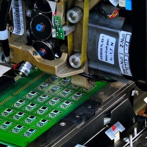 A close-up view of a precision mechanical component with a green electronic circuit board 