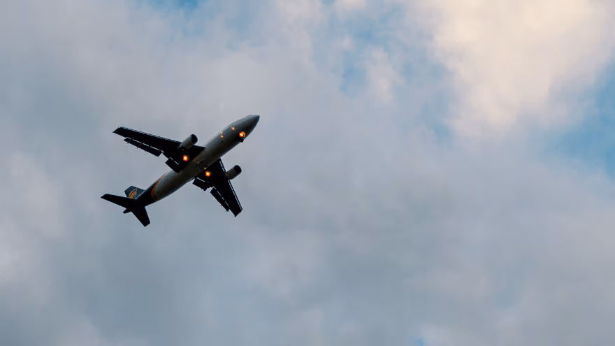 Black airplane in blue sky amongst clouds