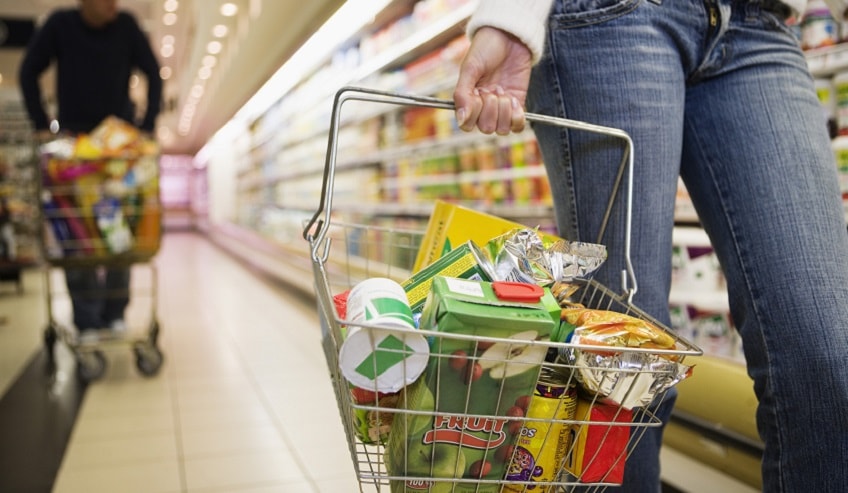 Woman shopping with a full basket at a grocery store. 