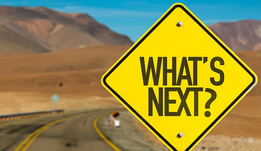 Sign in front of mountains that reads "What's next?"