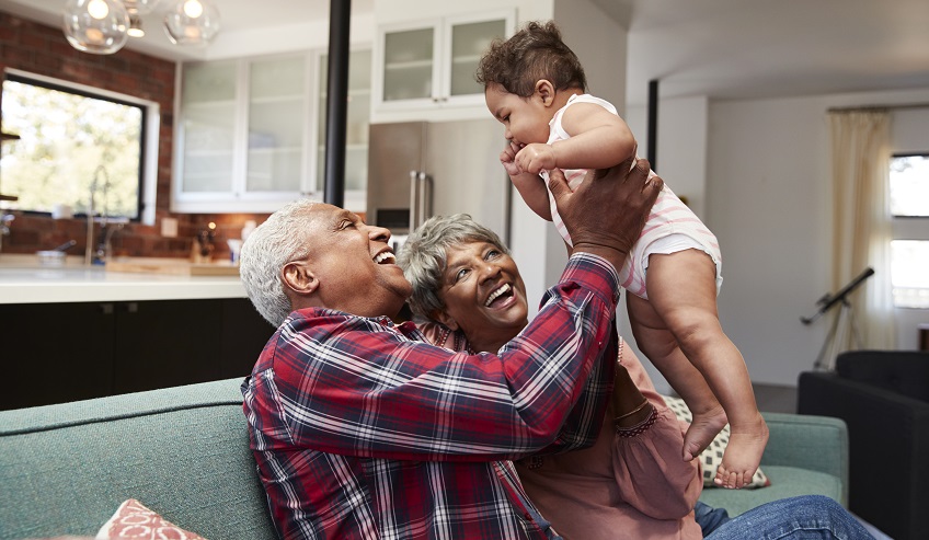 Grandparents holding a baby and smiling