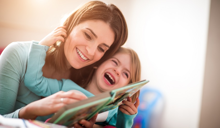 Woman and child reading a book and laughing