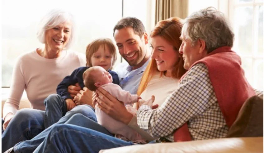 Parents and grandparents smiling at a newborn baby