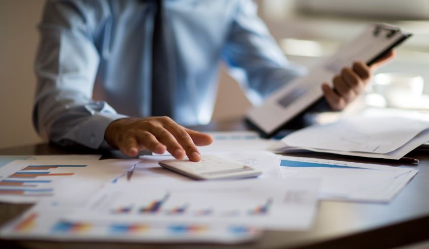 Business man with calculator and graphs