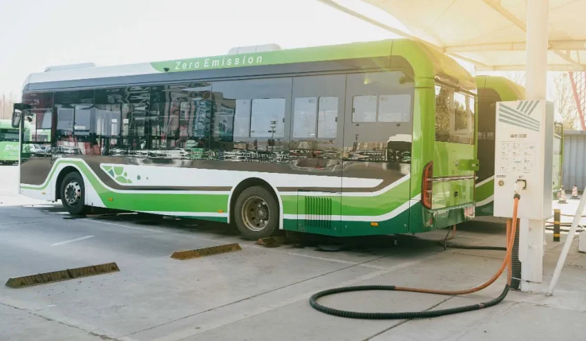 Green white bus parked at EV charging station