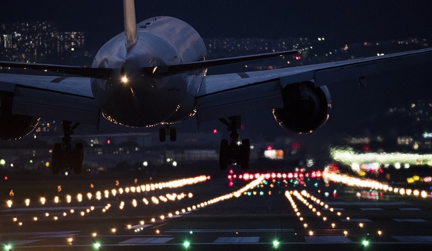 Airplane landing at night guided by runway lights. 