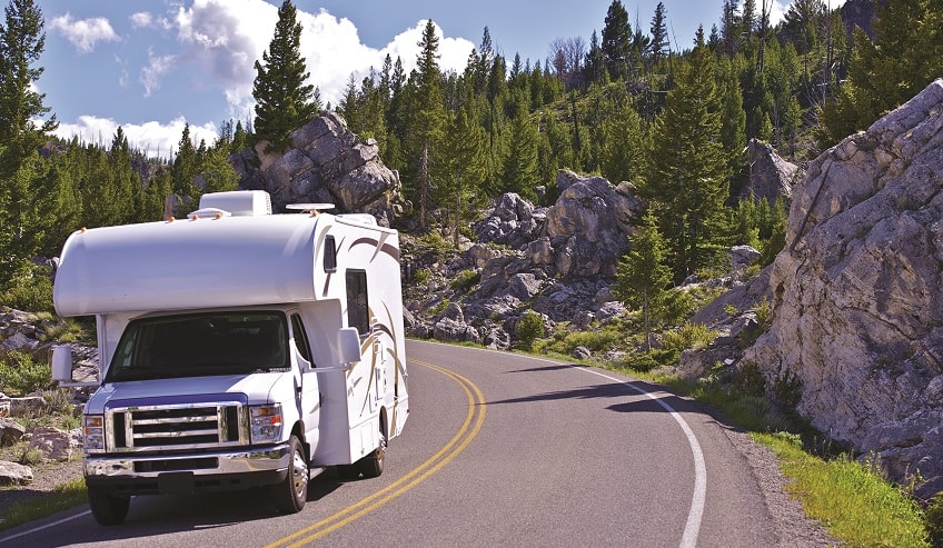 RV driving down the road in the mountains.