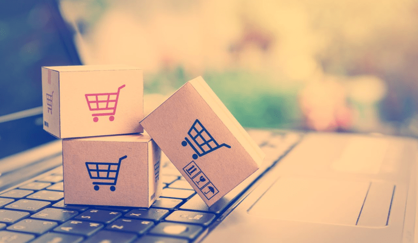 Shopping carts on tiny ecommerce  boxes on top of a laptop