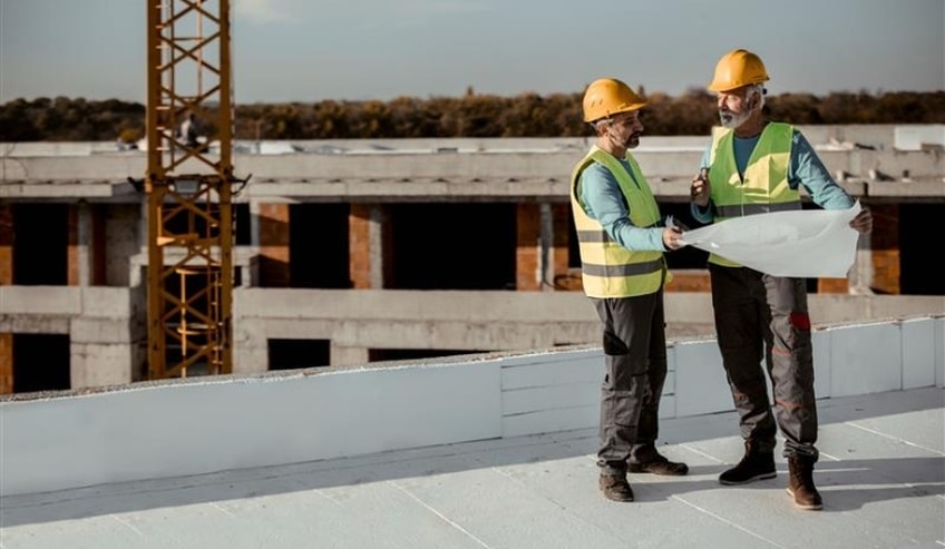 Workers studying roofing plan on rooftop